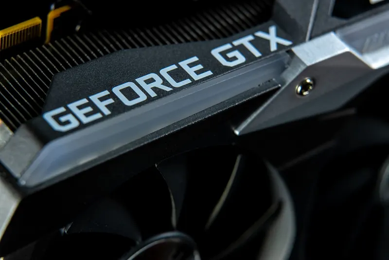 Macro photograph of a GeForce GTX graphics card showing its cooling fins, fan, and metal shroud